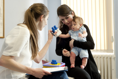Female osteopath with mother and baby