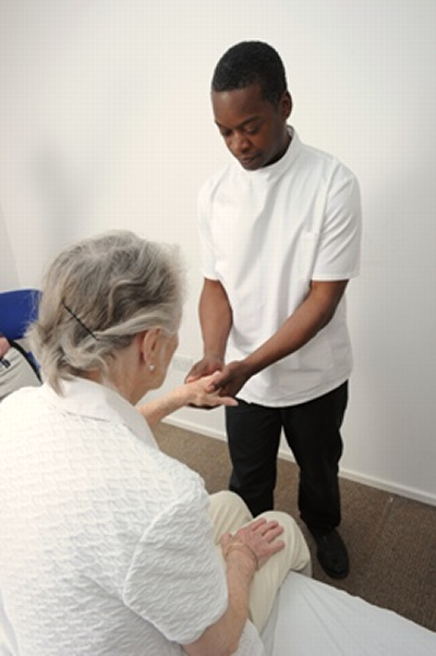 Male osteopath treating female patient's hand