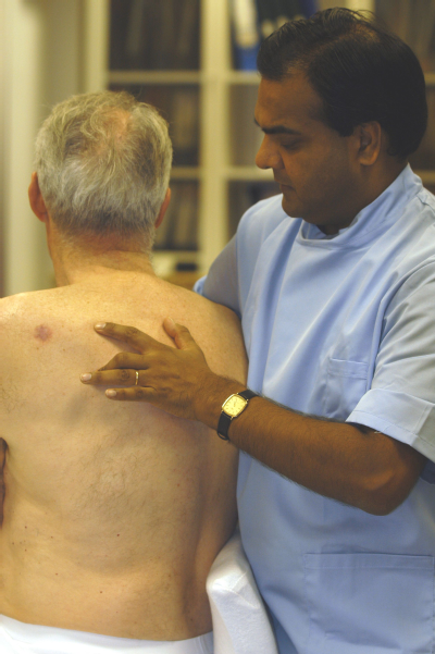 Male osteopath and middle aged man - back