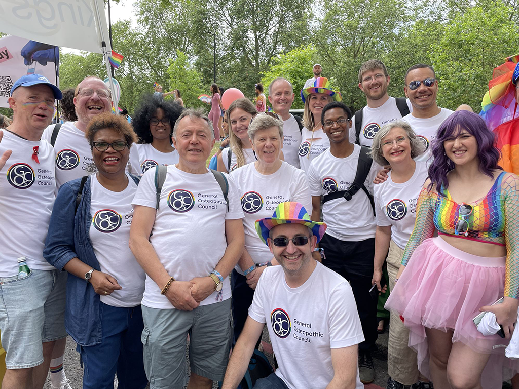 A group of GOsC staff, osteopaths and stakeholders posing in GOsC Pride logo tshirts in Pride in London 2023